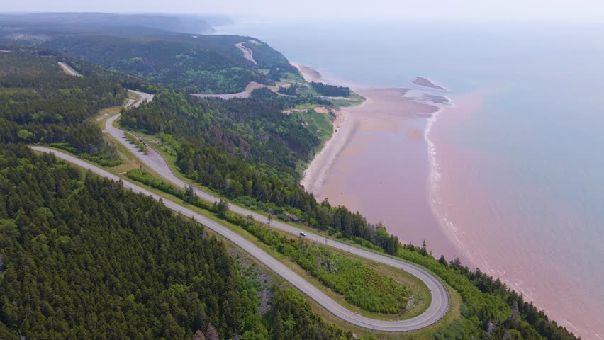 Aerial shot of one of the most famous landscapes in Canada located at the Bay of Fundy trail in New Brunswick where the highway is close by the massive cliffs edge with the beach in the background.