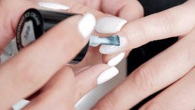 4K Close up video of beautician painting nails of a female client in a beauty center. White nails, coconut color. Concept: well being
