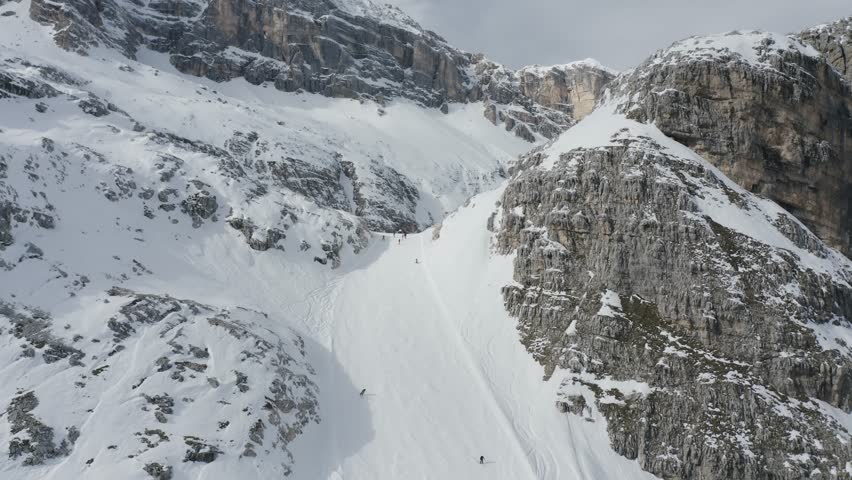 Expert skiers descend steep slopes Cortina Tofane mountain, Dolomites winter sport activity
