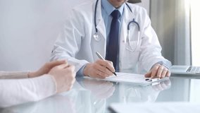 Doctor is consulting patient in modern fair clinic. Healthcare professional discusses medical information with a woman, gesturing above the glass desk. Medicine - Powered by Shutterstock - Get 15% off with code: PIKWIZARD15