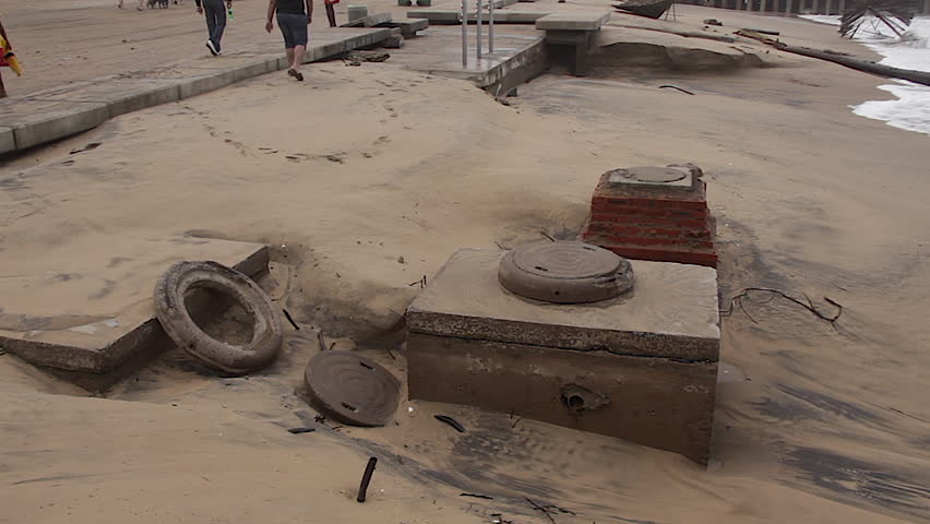Impact of severe storm damage in Durban: showing debris, broken umbrellas, and beach erosion exposing manholes.