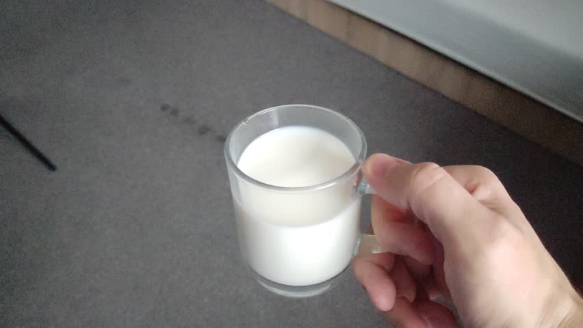 Man holding a transparent glass mug with milk in his hand at home