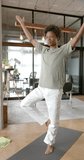 Vertical video of african american man doing yoga and meditating at home, slow motion. Lifestyle, relaxation, self care and domestic life, unaltered.