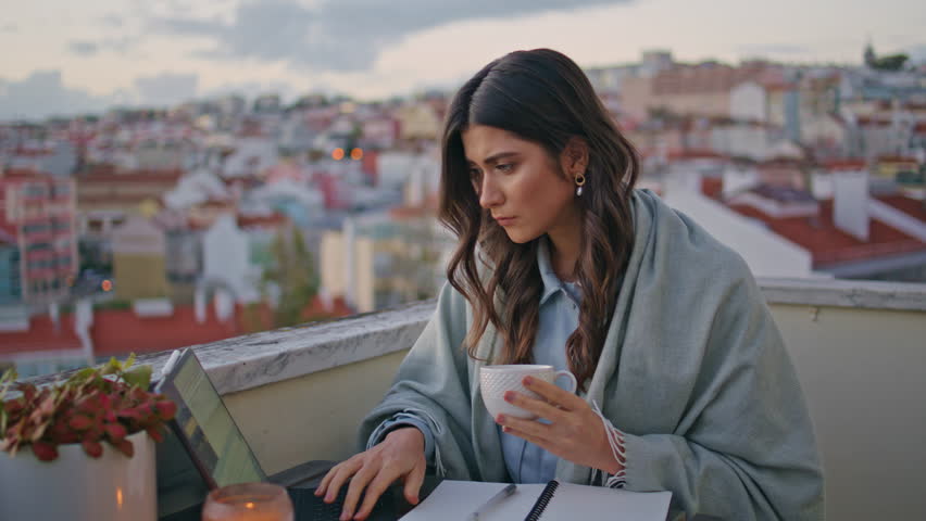 Lady author holding tea cup working at panorama terrace at evening closeup. Serious woman taking pen looking computer screen at sunset rooftop. Focused student girl watching webinar using laptop alone - Powered by Shutterstock - Get 15% off with code: PIKWIZARD15