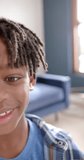 Vertical video of portrait of happy african american boy smiling at home, slow motion. Childhood and domestic life, unaltered.