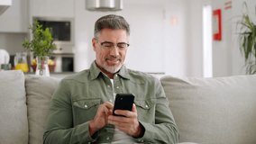 Happy relaxed mature man using cellphone relaxing on couch at home. Middle aged old user holding smartphone browsing internet, texting messages on mobile cell phone technology sitting on sofa. - Powered by Shutterstock - Get 15% off with code: PIKWIZARD15