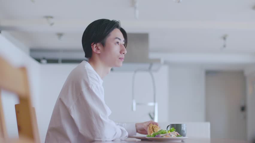 Young Japanese man eating breakfast in the living room Royalty-Free Stock Footage #3474490781