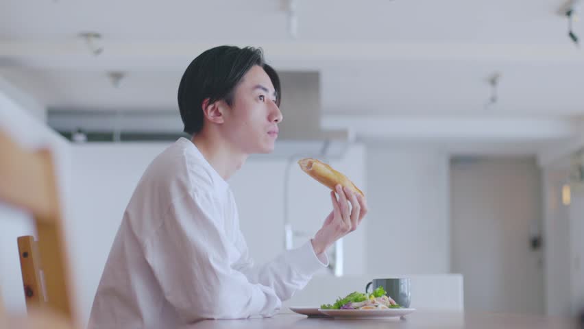 Young Japanese man eating breakfast in the living room