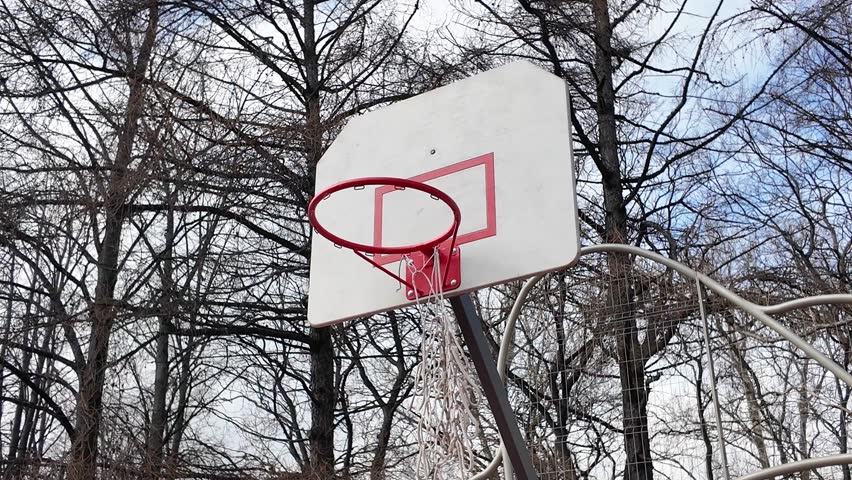 A basketball hoop in the yard with a torn net. Throwing the ball into the hoop Royalty-Free Stock Footage #3474532133