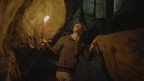 Man holding candle in dark cave, creating art with shadows on soil walls - Powered by Shutterstock - Get 15% off with code: PIKWIZARD15