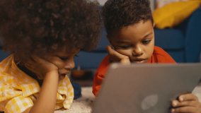 Two little African American brothers watching videos on tablet, gadget users