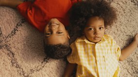 Portrait of two cute African American brothers lying on carpet, happy childhood - Powered by Shutterstock - Get 15% off with code: PIKWIZARD15