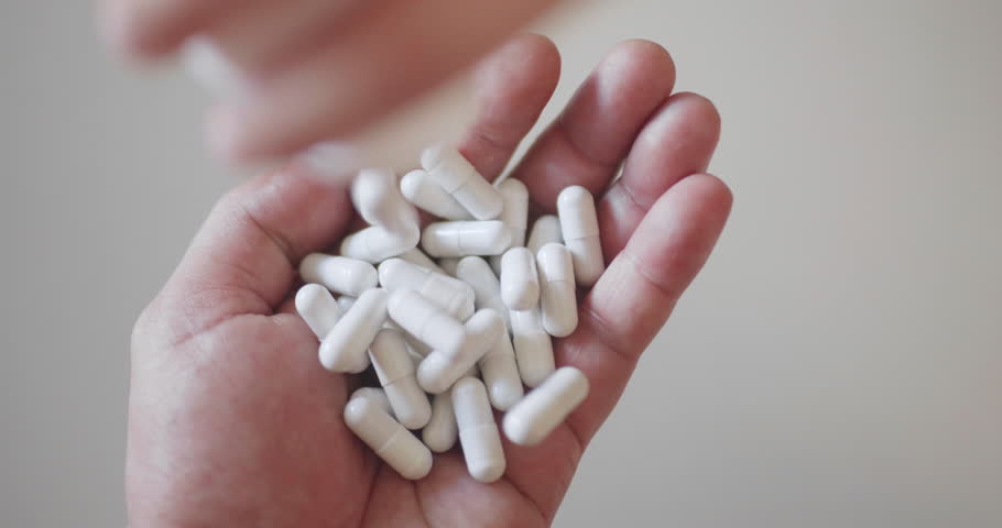 Close up shot of pills being poured into hand.
