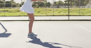 Video of midsection of caucasian female tennis player holding racket and training with friend. professional tennis training, sport and competition concept.