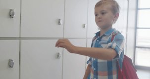 Video of caucasian boy closing locker and smiling at school. primary school education, knowledge and learning concept.