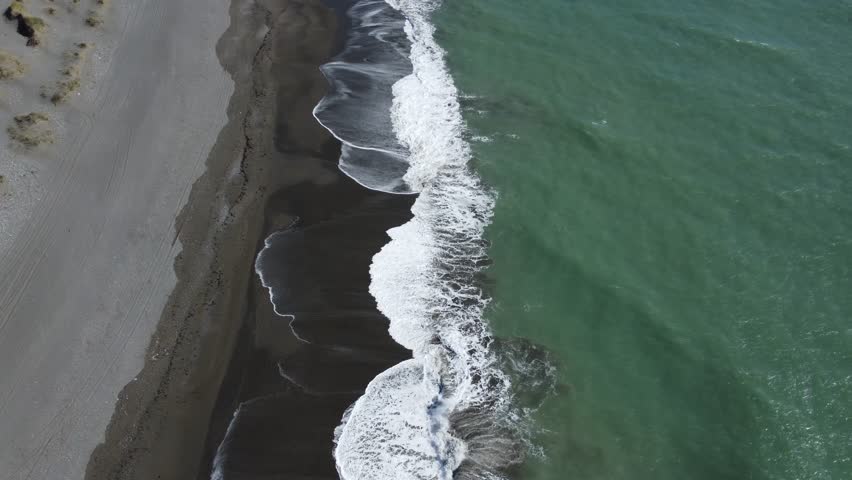 Waves breaking onto a black beach deep green sea camera panning along beach of of Southern Patagonia Argentina Tierra del Fuego island or Big Island of the Land of Fire