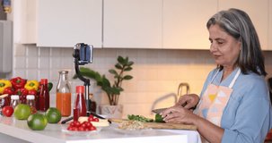 Happy mature woman following online cooking lesson