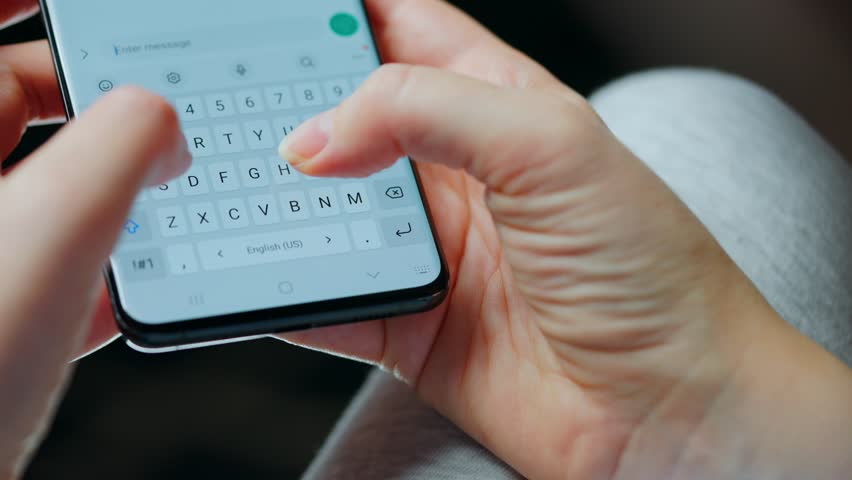 Female hands typing text on smartphone close-up.