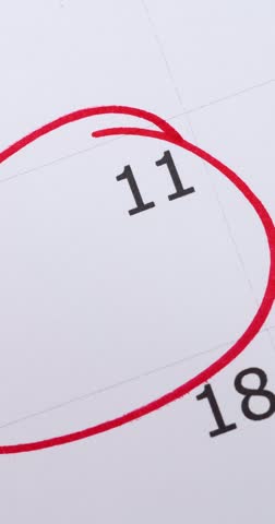 Portrait video footage of calendar showing the number 11 with a males hand circling the date with a red pen, save the date or appointment reminder concept.