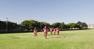 Video of happy diverse group of football players running on field with ball. Male football team, inclusivity and fitness in team sports.