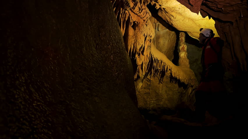 A speleologist with a headlamp exploring a cave with rich stalactite and stalagmite formations. High quality 4k footage Royalty-Free Stock Footage #3474811445