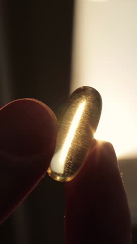 Male hand fingers show pills with cod liver oil omega 3 gel capsules medicine drug. Vertical video.