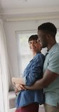 Vertical video of happy diverse couple embracing at home. family spending time together at home and body inclusivity.