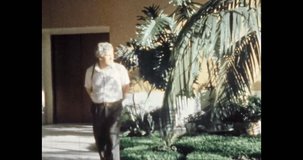 Man walking in light room with tropical plants. Green plants cast beautiful shadow on businessman. Man reflecting on life. Archival vintage color film. Archive video. Old retro 1980s Moscow Russia