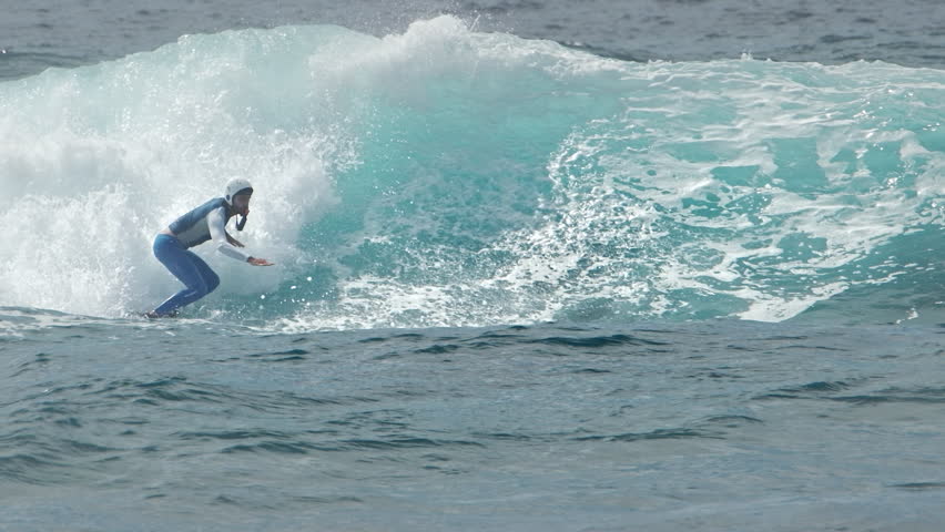 Surfer in protective helmet rides the wave in the Maldives