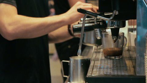 Barista making coffee in coffee machine at a busy coffee shop