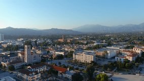 panning aerial footage of the bell tower at city hall with office buildings, shops and apartments in the city skyline in Pasadena California USA