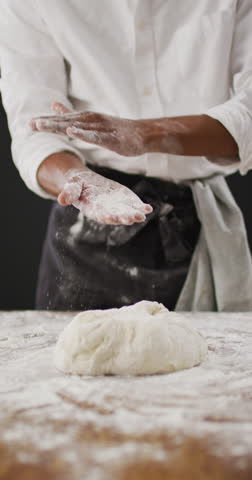 Vertical video of midsection of baker dusting hands with flour before kneading dough. healthy food preparation, diet and nutrition. Royalty-Free Stock Footage #3475004349