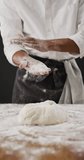 Vertical video of midsection of baker dusting hands with flour before kneading dough. healthy food preparation, diet and nutrition.
