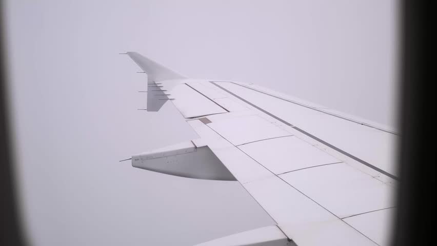 View on an airplane wing in clouds through a porthole. Cloudy sky background. A passenger plane flying in fog. Bad weather and visibility. Concept of people's fear traveling by air. Aerophobia. 4K. Royalty-Free Stock Footage #3475004515