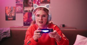 Headphones, face and woman playing video game in house for competition, rpg and online. Controller, girl and person on console technology for entertainment with neon light in portrait at apartment