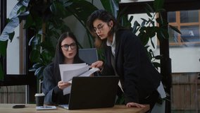 Two girls in a office discuss documents or a project on paper. Teamwork in coworking. Businesswomen in glasses create a marketing plan. Caucasian female people are working on a laptop. Modern office - Powered by Shutterstock - Get 15% off with code: PIKWIZARD15