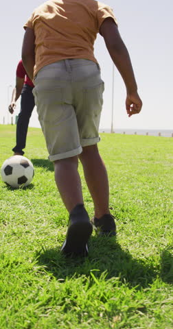 Vertical video of african american father with son playing football. spending free time during holiday.