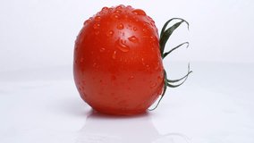 4K video of one tomato slowly rotating on white background