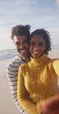 Vertical video of portrait of happy biracial couple on sunny beach. healthy, active time beach holiday.