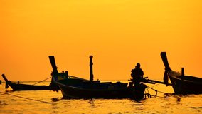 Travel video Group of silhouette long tail boat and The fisherman are maintenance ship. After the boats go out, such as catching the fish. Trips are made every day with golden light before sunset