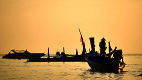 Travel video silhouette long tail boat and The fisherman are maintenance ship. After the boats go out, such as catching the fish. Trips are made every day with  golden light of the Sun before sunset