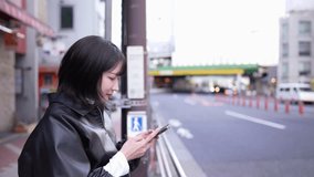 Slow-motion video of a Japanese woman stopping and operating her smartphone around Gotanda Station, Shinagawa-ku, Tokyo in winter
