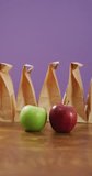 Vertical video of red and green apple with row of packed lunches in paper bags and purple background. healthy diet, food and nutrition.