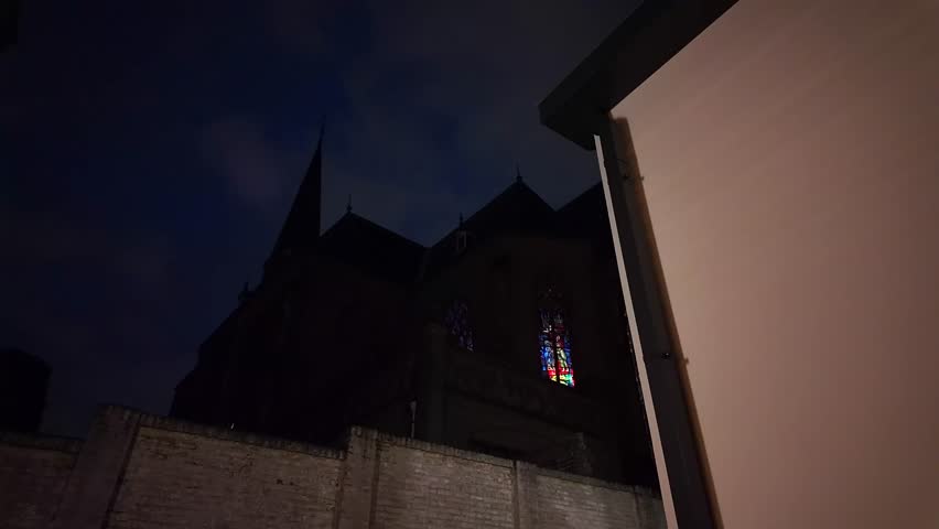 Silhouette of catholic church at night with blue dark sky and white wall