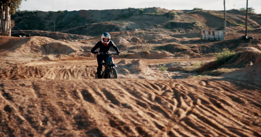 Man, motorcycle and desert for race, adventure or action outdoor with jump stunt at rally. Bike, professional rider and person on dirt road for sports, fast or speed for training on sand in Dubai