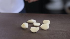 Chef using knife to smashing the fresh garlic on a cutting board, prepare for cooking. 4k slow motion 100fps video.