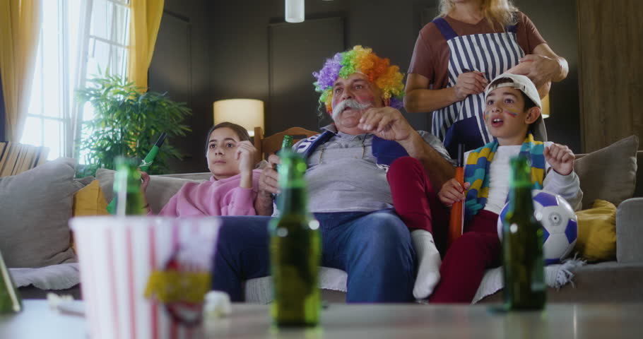 Grandparents and grandchildren watching football match and celebrating victory score in the living room. Royalty-Free Stock Footage #3475380811