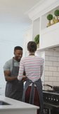 Vertical video of happy diverse couple dancing at home. family spending time together at home and body inclusivity.