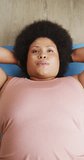 Vertical video of plus size biracial woman exercising at home. spending active time at home and body inclusivity.