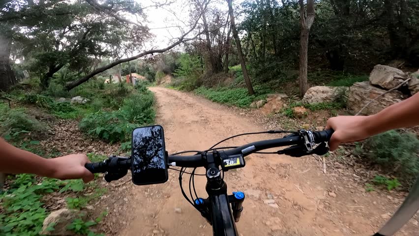 An unrecognizable person riding a bicycle through a narrow dirt road in the countryside on a cloudy day. Go pro action camera. POV. People in active sports, leisure and entertainment mode Royalty-Free Stock Footage #3475464889